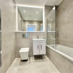 Modern bathroom with bath, sink, and towel rail.