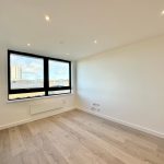 Empty room with wooden floor and large window.