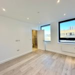 Bright unfurnished room with large windows and wood floor.