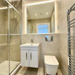 Modern bathroom with shower, sink, and heated towel rail.