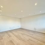 Empty modern room with wooden flooring and spotlights.