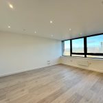 Spacious unfurnished room with large windows and wooden floor.