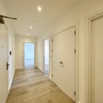 Modern hallway with wooden floor and white doors.