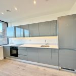 Modern kitchen with grey cabinets and stainless appliances.