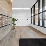 Modern building lobby with mailboxes and large windows.