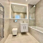 Modern beige bathroom with large mirror and tub