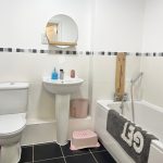 Modern bathroom with toilet, sink, and bath.