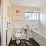 Modern bathroom with shower, bathtub, and white tiles.