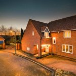 Cosy brick house with driveway at sunset.