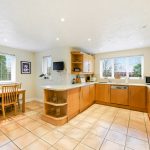 Spacious modern kitchen with wooden cabinets and dining table.