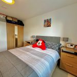Cosy bedroom with plush toy and wooden furniture.