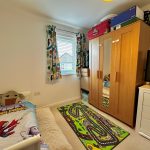 Bright children's bedroom with toys and mirrored wardrobe.