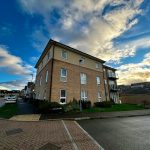 Modern apartment building under a cloudy blue sky.