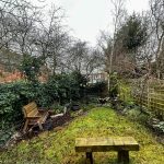 Winter garden with wooden bench and bare trees.