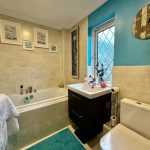 Modern bathroom with teal walls and artwork decor.