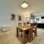 Modern dining room with kitchen in background.