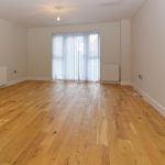 Spacious room with wooden floor and large window.