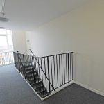Bright stairwell with window view and black railing