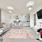 Modern living room with grey sofas and kitchen view.