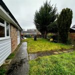 Suburban garden with grass and pathway beside house.