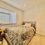 Cosy bedroom with floral bedspread and window view.