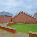 Backyard with red brick walls and green lawn.