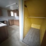 Empty kitchen with wooden cabinets and small yellow pantry.