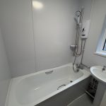 Modern bathroom with bathtub and electric shower.