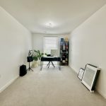 Minimalist home office with desk and bookshelf.