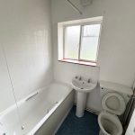 White bathroom with bath, sink, toilet, window.