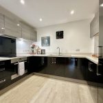 Modern kitchen with sleek cabinets and wood flooring.