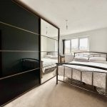 Bedroom with mirrored wardrobe and double bed.