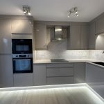 Modern kitchen with grey cabinets and marble backsplash.