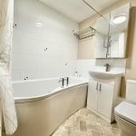 Modern bathroom with bathtub and white fixtures.