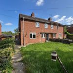 Brick semi-detached house with garden and path.