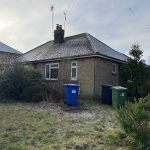 Single-storey house with frost-covered lawn and bins