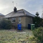 Single-storey house with bins in front garden.