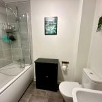 Modern bathroom with bathtub, toilet, and wall decor.