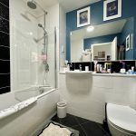Modern bathroom with blue walls and black tiles.