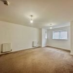 Spacious room with beige carpet and natural light.