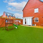Brick house with artificial grass garden and play frame.