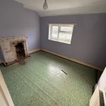 Empty room with fireplace and green flooring.