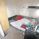 Messy bedroom with cluttered bedside table.