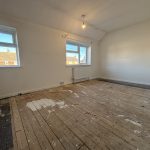 Empty room with bare wooden floorboards.