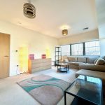Modern living room with beige sofa and large windows.