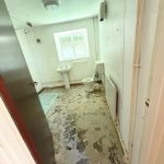 Empty bathroom with peeling floor and window view.