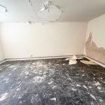 Empty room with damaged floor and peeling paint.