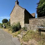 Rural stone cottage on Blacksmiths Lane, sunny day.