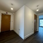 Modern apartment hallway, wooden doors, and bright lighting.