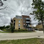 Newly constructed brick building with scaffolding under cloudy sky.